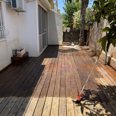 מרפסת עץ עם כלי צביעה ומברשת על הרצפה