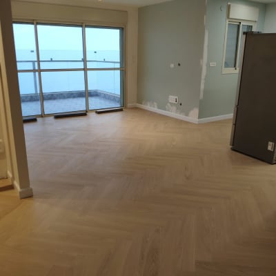 רצפת פרקט עץ בהתקנה בחדר ריק עם חלון גדול