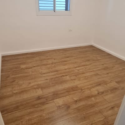 רצפת פרקט עץ בחדר ריק עם קירות לבנים