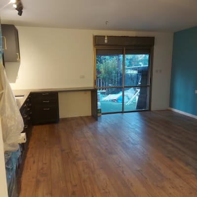 מטבח עם ארונות כהים ומשטח עבודה לבן