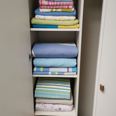 מדפים עם מצעים מקופלים בארון לבן