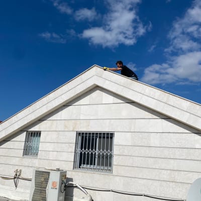 אדם עובד על גג רעפים עם כפפות צהובות