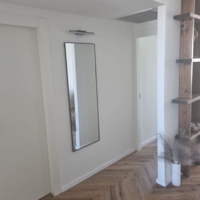 מראה תלויה על קיר עם מנורה מעליה