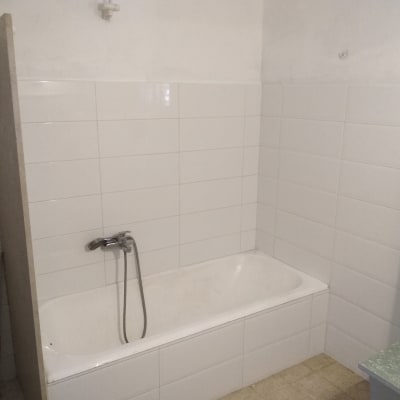 חדר אמבטיה עם אריחים לבנים ואמבטיה מותקנת