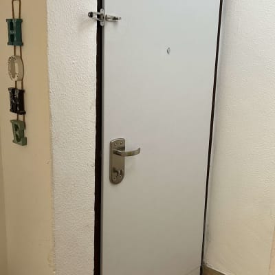 דלת לבנה עם ידית מתכת ובריח עליון