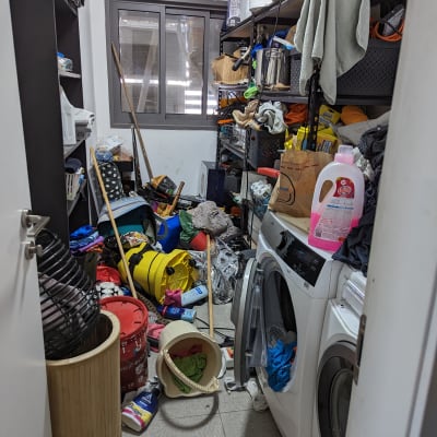 חדר כביסה מבולגן עם מדפים עמוסים וחומרי ניקוי