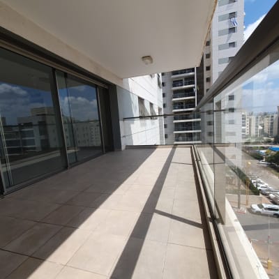 מרפסת עם רצפת אריחים נקייה ומעקה זכוכית.