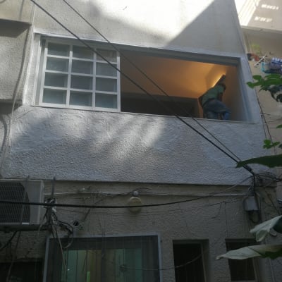 אדם עובד על איטום חלון בקומה שנייה