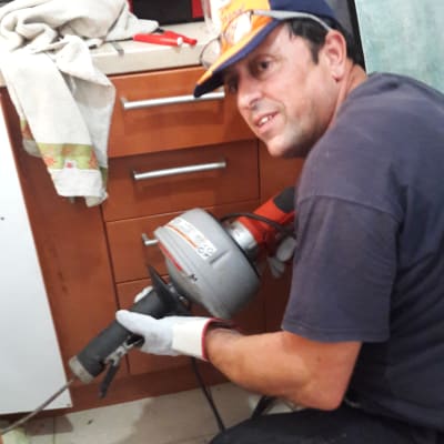 אדם עם כלי עבודה לפתיחת סתימות במטבח