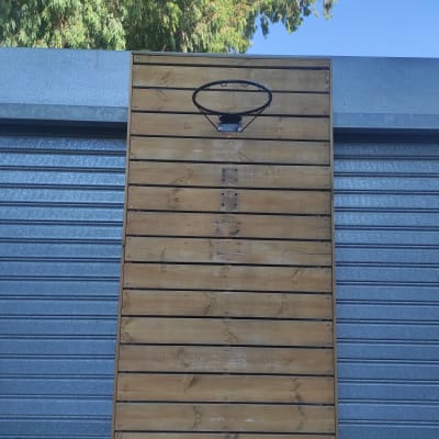 לוח עץ עם טבעת כדורסל מותקנת על קיר מתכת