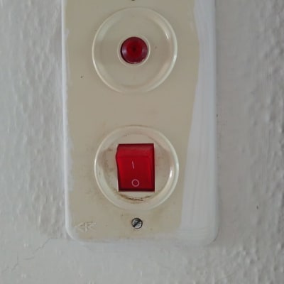 מתג חשמלי עם נורית חיווי אדומה על קיר