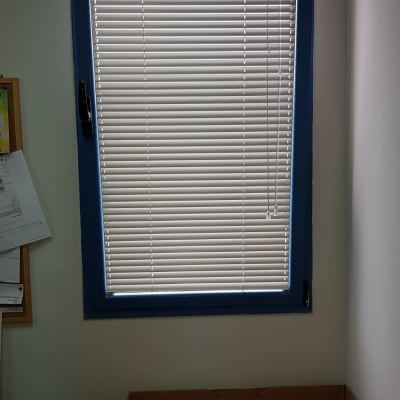 תריסים לבנים על חלון עם מסגרת כחולה