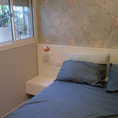 מיטה עם כריות כחולות וטפט פרחוני על הקיר