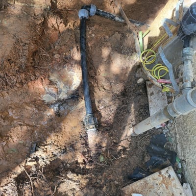 צינור מים שחור עם מחברים באדמה רטובה