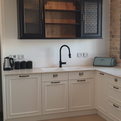 מטבח עם ארונות לבנים, כיור וברז שחור, קומקום חשמלי