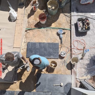 עובדים מניחים אריחים עם כלים וחומרים לריצוף