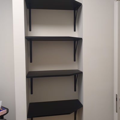 מדפים שחורים מותקנים על קיר עם תומכים מתכתיים