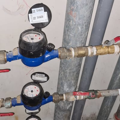 מד מים כחול עם ברזים אדומים וצינורות מתכת