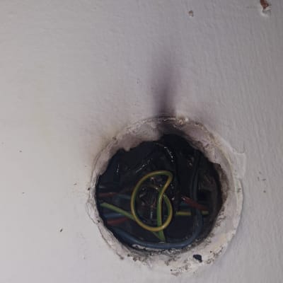 חוטי חשמל צבעוניים בקיר עם סימני שריפה