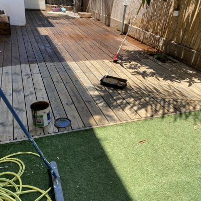 מרפסת עץ עם כלי צביעה ודלי צבע פתוח