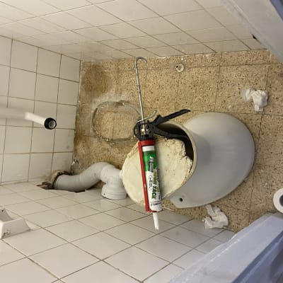 חדר אמבטיה עם צינור, דלי, ואקדח סיליקון