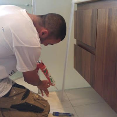 אדם משתמש באקדח סיליקון ליד ארון עץ.