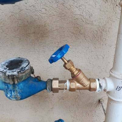 מד מים כחול עם ברז זהב על צינור לבן