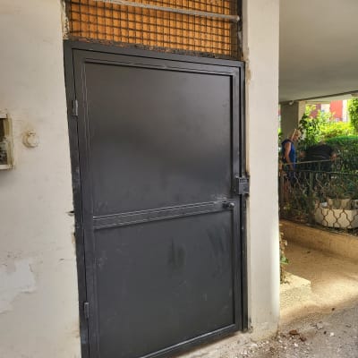 דלת מתכת שחורה עם מסגרת רשת מעליה