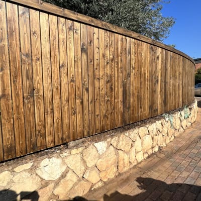 גדר עץ על קיר אבן לצד מדרכה