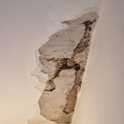 קיר עם טיח מתקלף וחור בתקרה