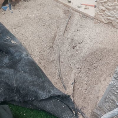 כבלים חשמליים מונחים בחול ליד קיר אבן