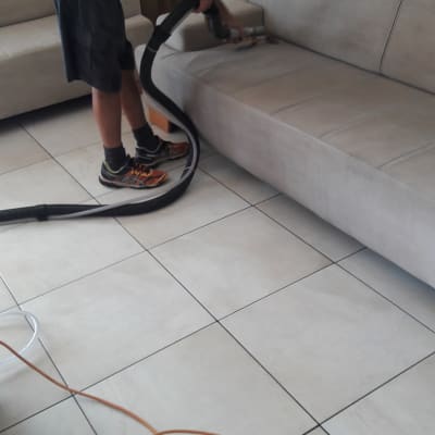 אדם מנקה ספה עם שואב אבק מקצועי