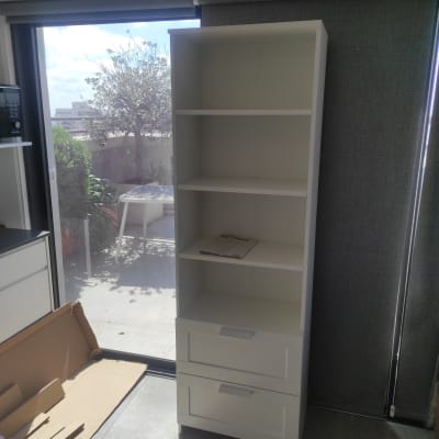 ארון לבן עם מדפים ומגירות, קרטון על הרצפה