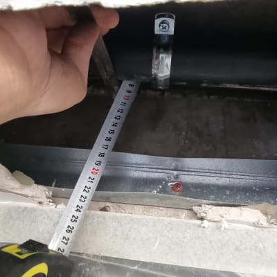 יד מחזיקה סרט מדידה ליד צינור מתכת