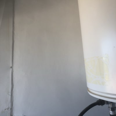 קיר צבוע בצבע אפור בהיר עם חור קטן