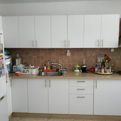 מטבח עם ארונות לבנים, כיור וכלים על השיש