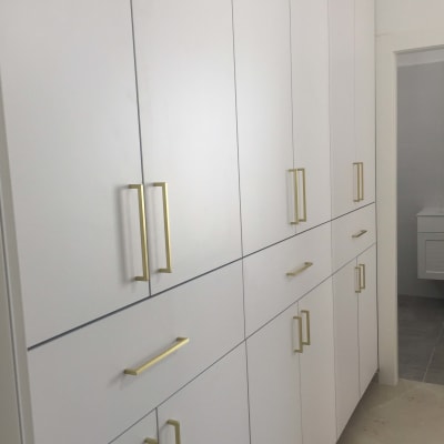 ארונות לבנים עם ידיות זהב מותקנים בקיר