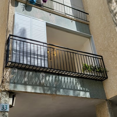 מרפסת עם מעקה מתכת שחור ותריסים לבנים