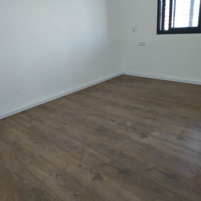 רצפת פרקט עץ כהה בחדר ריק עם קיר לבן