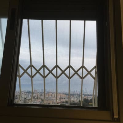 סורגי אלומיניום בחלון עם נוף עירוני