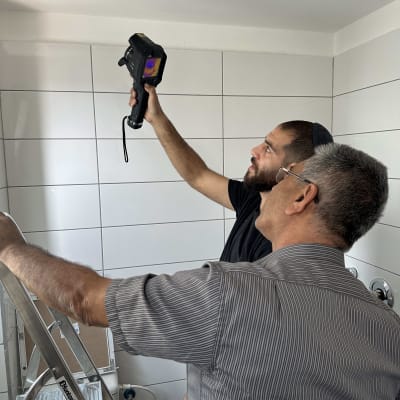 שני אנשים משתמשים במצלמה תרמית לבדוק נזילות בתקרה