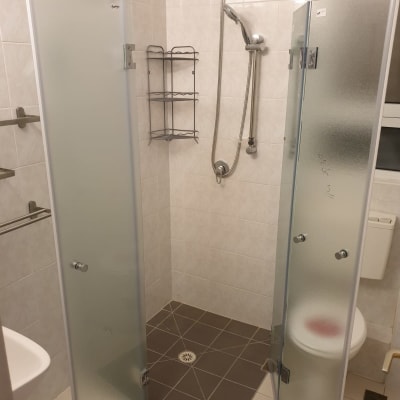 מקלחון עם דלתות זכוכית ומדף מתכת