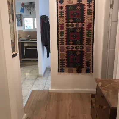 רצפת פרקט עץ במסדרון ביתי עם שטיח קיר צבעוני