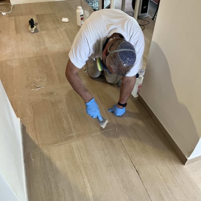 אדם עם כפפות צובע רצפה בעזרת מברשת