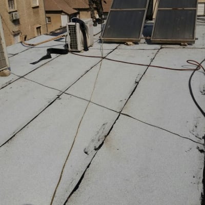 אדם על גג עם יריעות איטום וכלי עבודה