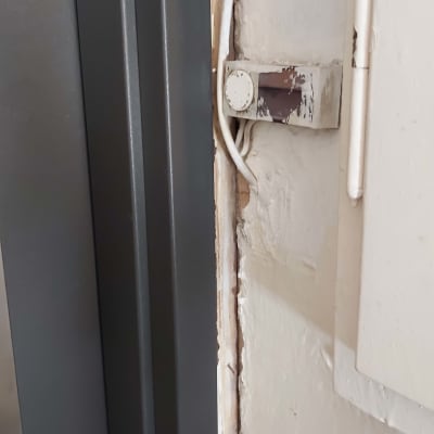 קיר צבוע עם קילופי צבע ליד דלת מתכת