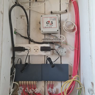 ארון תקשורת עם כבלים אדומים ושחורים, מתגים ותקעים