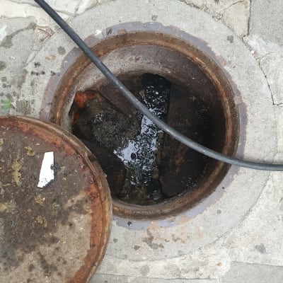 פתח ביוב פתוח עם כבל שחור וכלי עבודה