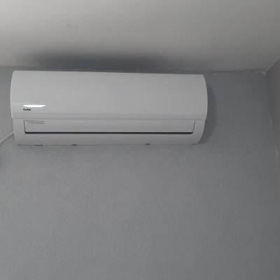 מזגן מותקן על קיר אפור עם שלט חוטי