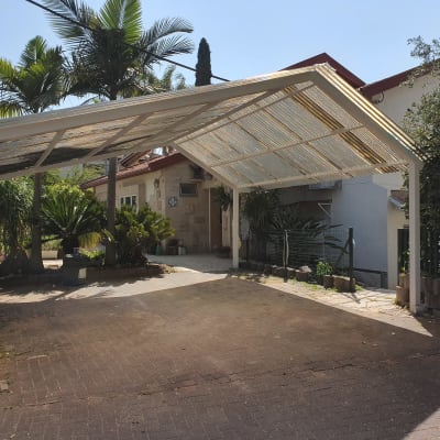 חניה מקורה עם גג עץ וגינה קטנה בצד